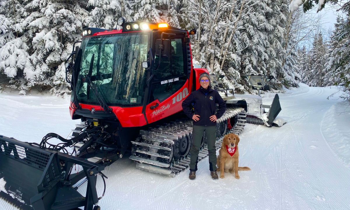 Ruth and her dog, Whiskey, posing with Kassbohrer Pisten Bully 100 ski trail grooming vehicle.